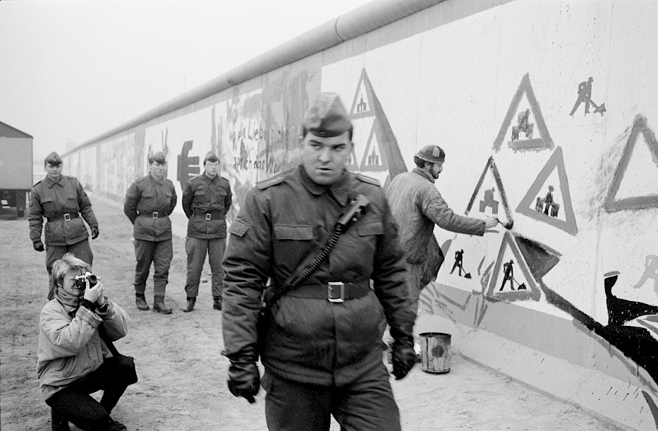 East Berlin artists painting the Wall at Potsdamer Platz while GDR border guards look on, November 1989