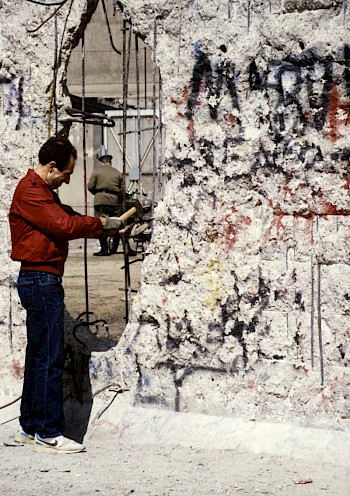 A man chipping pieces out of the former border wall, 1990